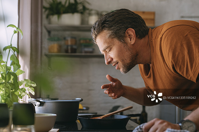 英俊的年轻男子在厨房里享受美食的香味图片素材