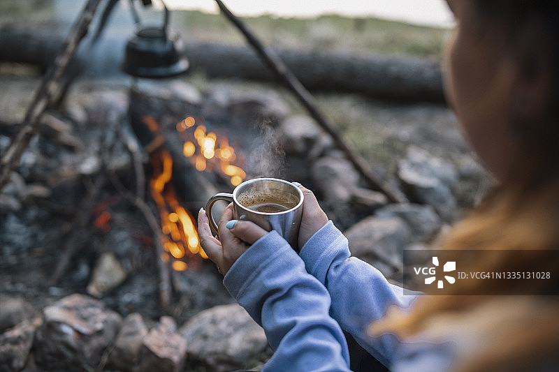 在篝火旁拿着热饮的女人图片素材