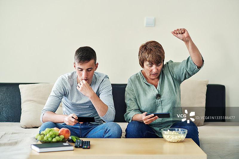 母亲和十几岁的儿子一起玩电子游戏图片素材