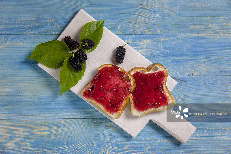 木桌上涂有桑葚果酱的切片面包图片素材