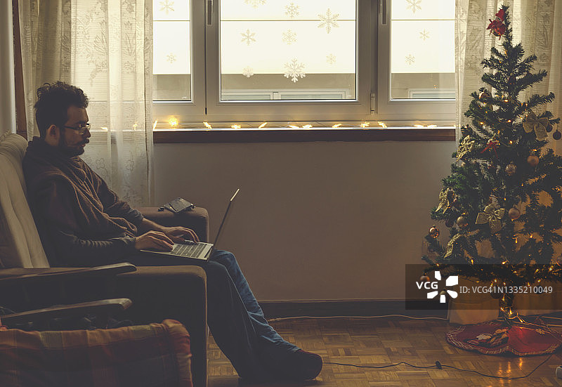 圣诞节期间在家工作的年轻男人图片素材