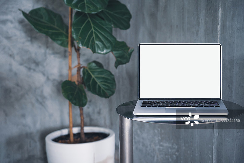 咖啡馆背景中桌子上带有空白白色屏幕的笔记本电脑。咖啡店模糊背景的桌子上带有空白屏幕的笔记本电脑。图片素材