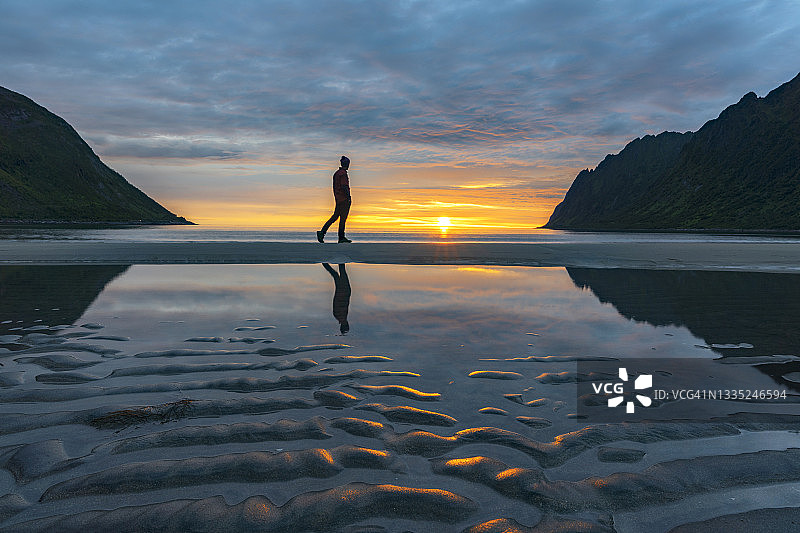 男子午夜在挪威塞尼亚海滩上行走图片素材