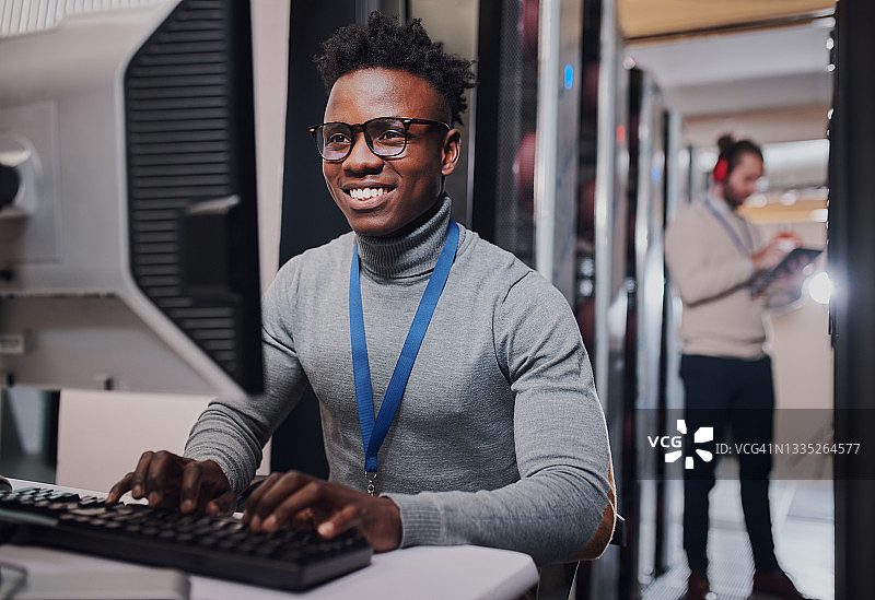 年轻男子在数据中心工作时使用电脑的镜头图片素材