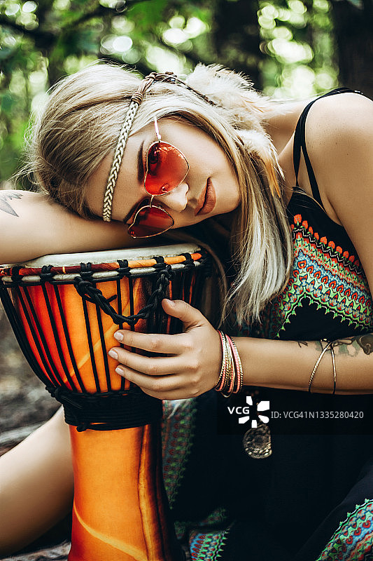 身穿民族嬉皮服装的漂亮女人躺在非洲鼓上图片素材