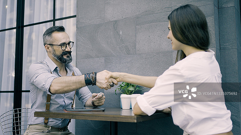 商务人士在户外咖啡馆握手达成商业交易图片素材