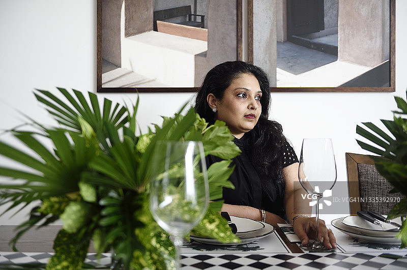 一位满足的女人坐在美丽的餐桌旁图片素材