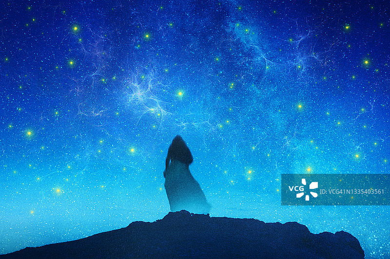 一个穿着连衣裙的幽灵般的女人看着满天繁星的神秘景象图片素材