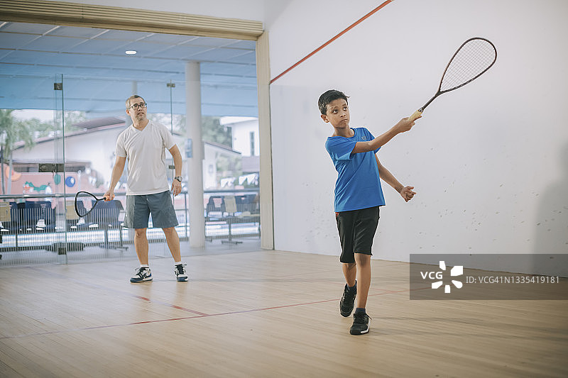 年轻的亚洲马来西亚男子在教练的指导下练习壁球图片素材