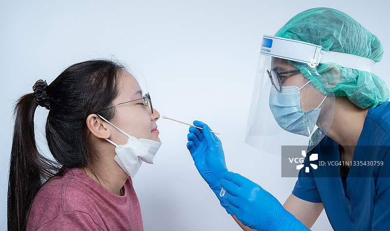 医护人员为亚洲女性进行新冠病毒检测的鼻拭子采样图片素材
