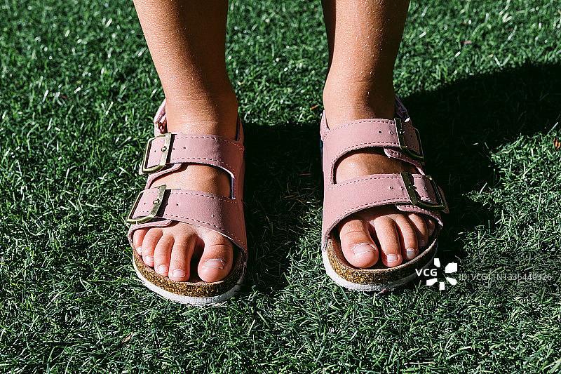 穿着粉色搭扣凉鞋的小女孩的脚部特写图片素材