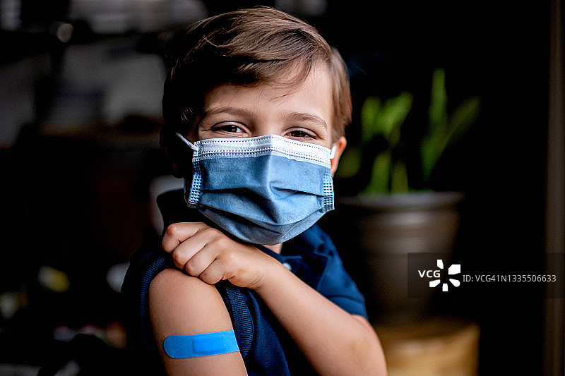 接种疫苗后展示创可贴的六岁儿童图片素材