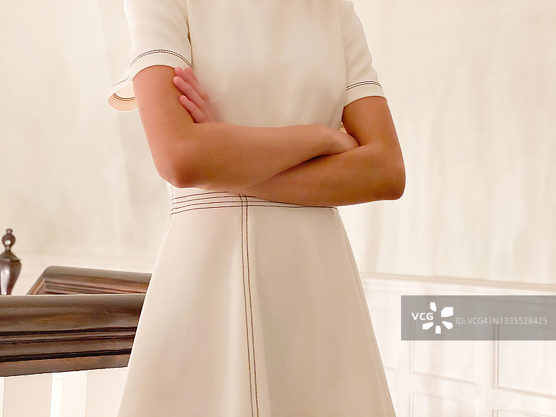 混血年轻女人抱臂穿白色连衣裙，出席特殊场合图片素材