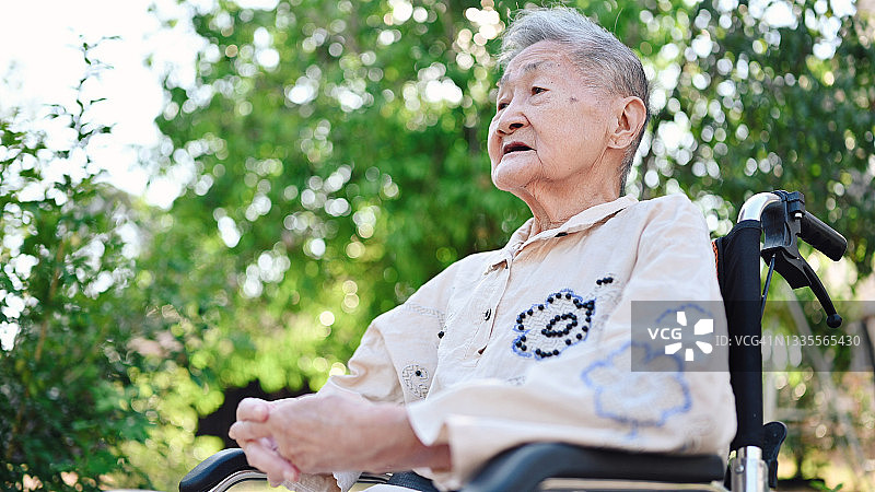 坐在轮椅上的快乐微笑失能奶奶在花园里放松身心图片素材