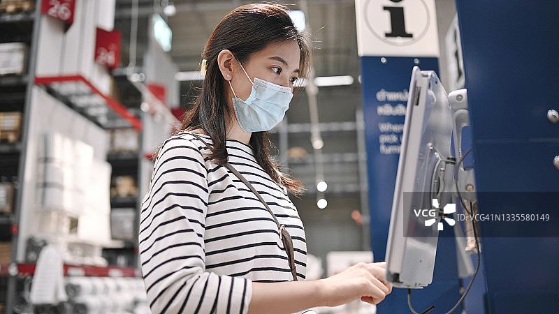 戴口罩的亚洲顾客在泰国超市使用自动售货机图片素材