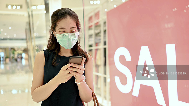 千禧一代和Z世代戴口罩在购物中心享受季末促销，百货商店促销特价优惠购物促销标志30%-50%促销图片素材