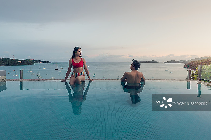 男女坐在游泳池旁，彼此对视图片素材