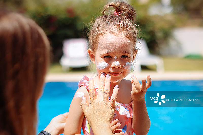 母亲在海滩上为小女儿涂抹防晒霜图片素材