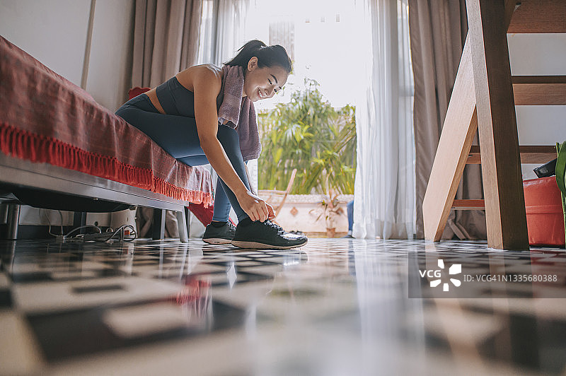 仰视角度：系鞋带的亚洲女运动员图片素材