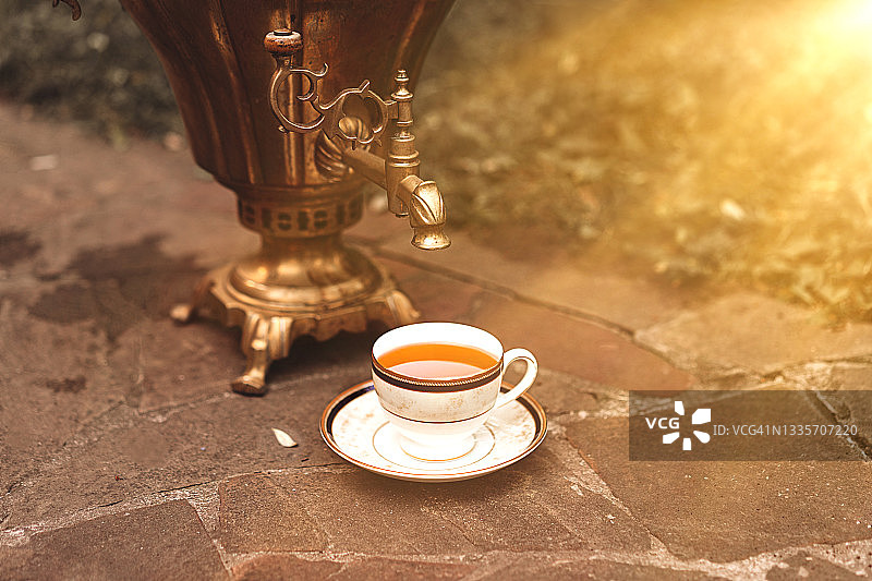 一杯热茶和一个俄式茶炊，秋日里以家庭院落为背景图片素材