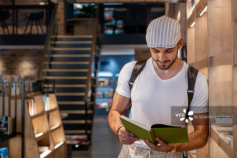英俊的年轻男人在书店里看书图片素材