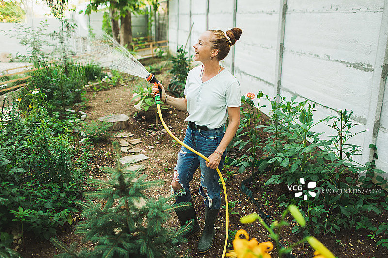 美丽可爱的女人在花园里浇花图片素材
