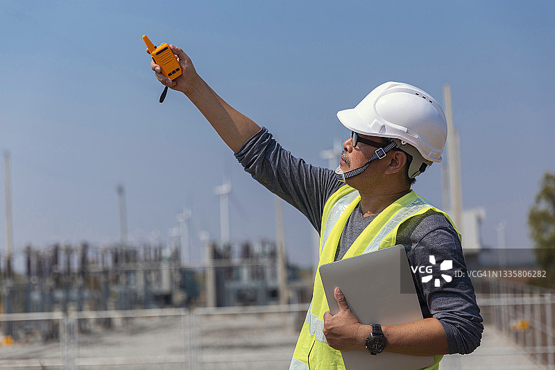 中年工程师使用对讲机与同事沟通，检查风力涡轮机质量控制效率，用于发电、可再生能源、清洁能源或环境保护理念图片素材