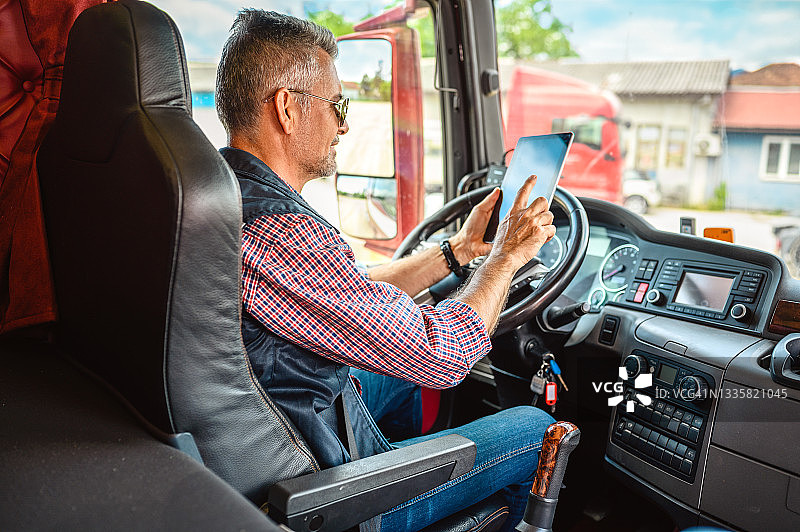 中年卡车司机使用手机App图片素材