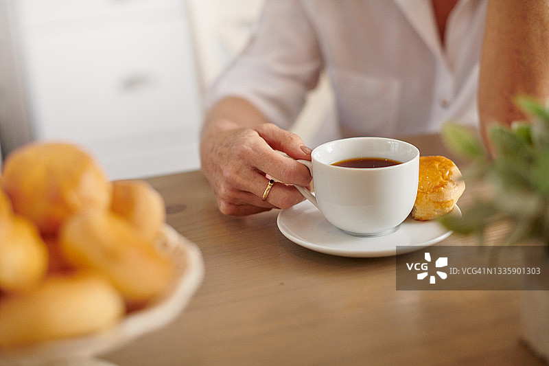 在家喝茶吃司康饼的女人（仅显示局部）图片素材