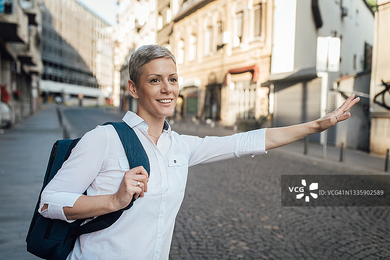 在城市里打电话叫出租车的女商人肖像图片素材