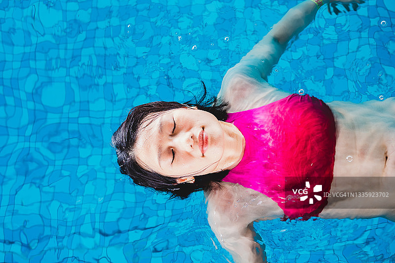 亚洲女性在游泳池放松漂浮图片素材