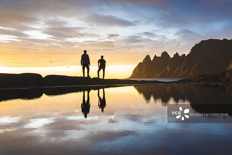 在挪威北部池塘边看日落的两个人图片素材