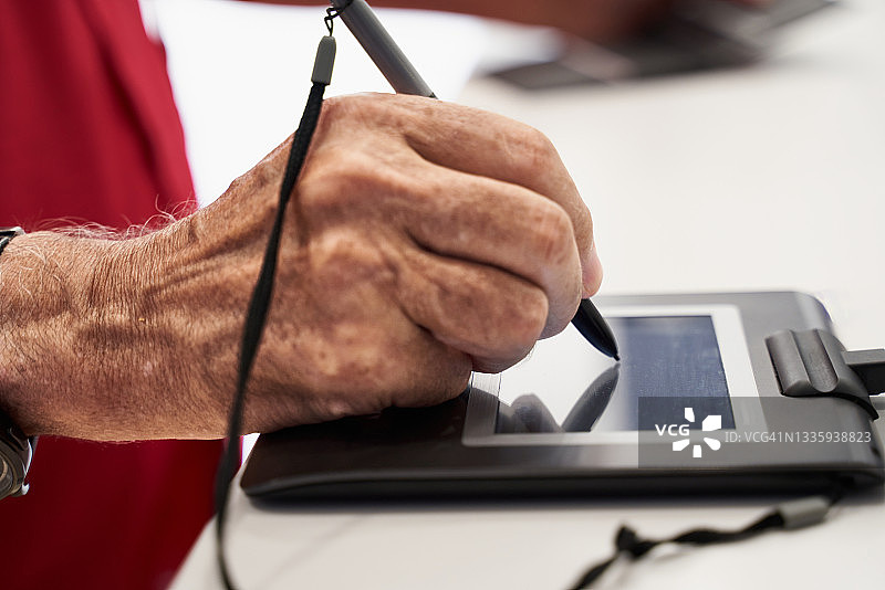 年长的白人男子在白色背景上使用数字化笔在数字平板上签署数字文件。图片素材