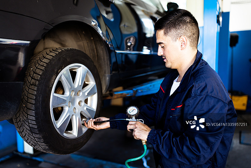 汽修工用压力表检查汽车轮胎并充气图片素材