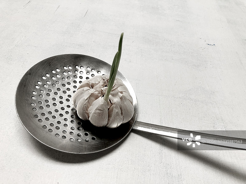 白色背景下的漏勺里的大蒜图片素材