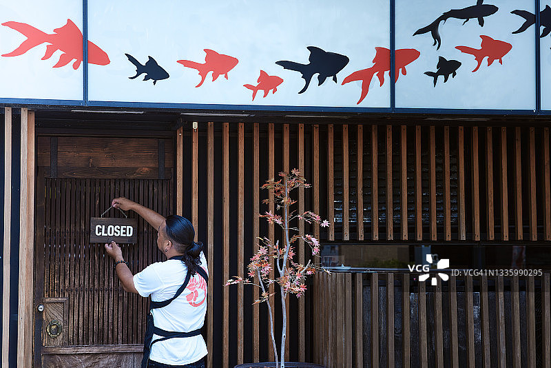 店主在开店前悬挂暂停营业标志图片素材