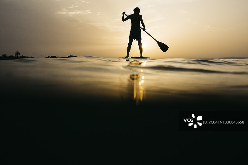 日落时划桨板的男孩图片素材