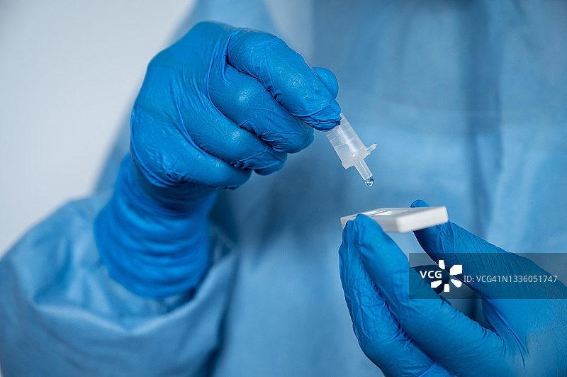 医护人员用抗原试剂盒进行新冠病毒鼻拭子检测后，挤压液体滴图片素材