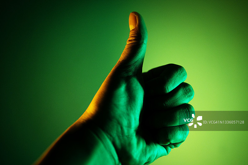 竖起大拇指的特写，绿色背景图片素材