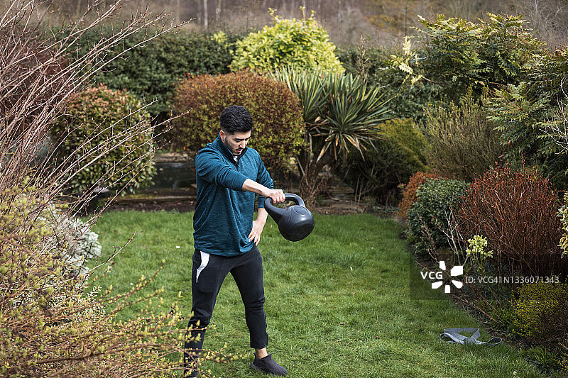 在花园里用壶铃训练的亚洲男人图片素材
