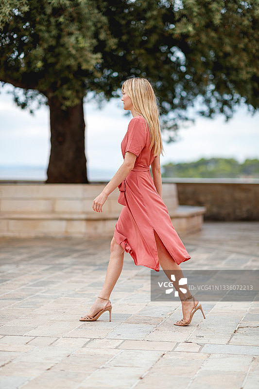 穿着高跟鞋走在达尔马提亚老城石板路上的优雅金发女郎图片素材