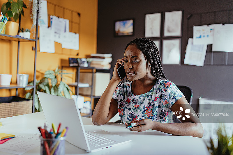 在家工作，使用手机和笔记本电脑的非洲年轻女性图片素材