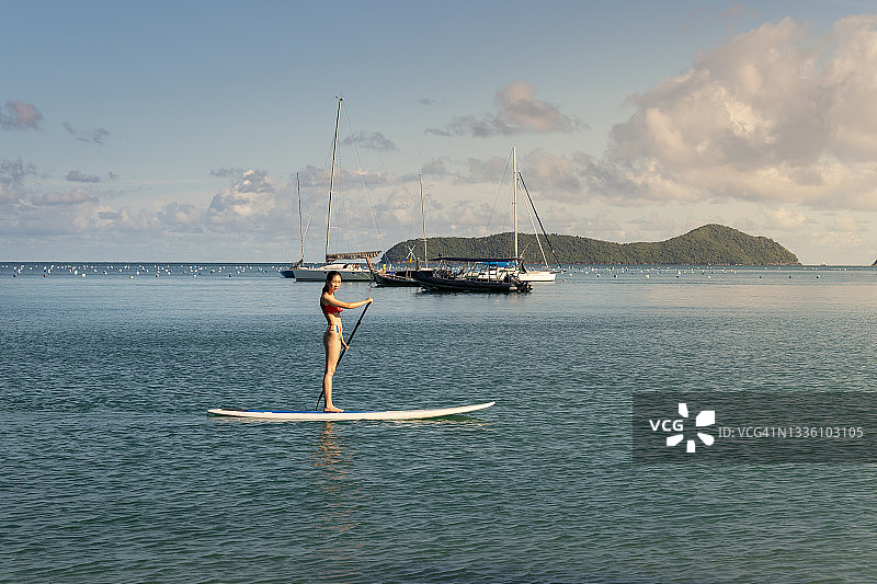 一名身穿泳衣的女子在海上划船，海上有许多船只图片素材