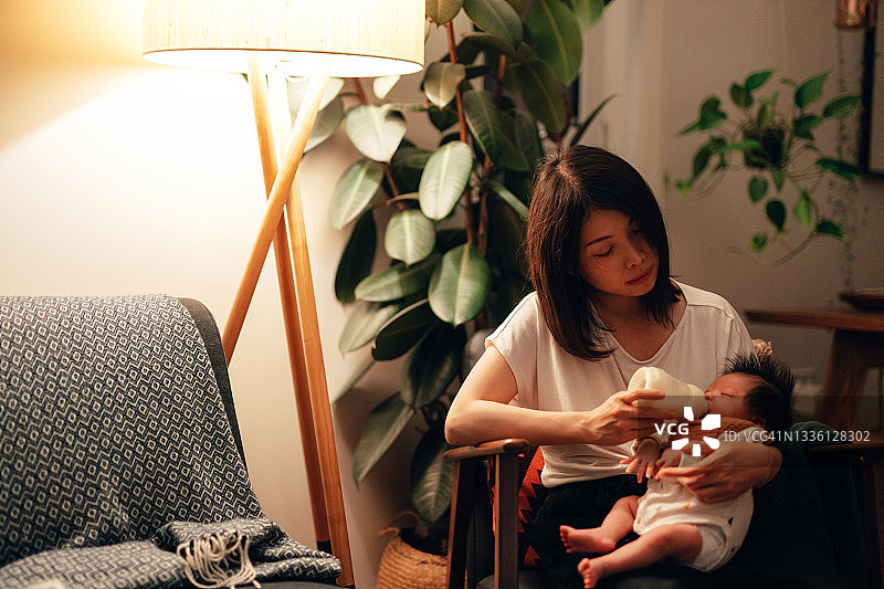 夜晚喂女儿时感到疲惫的母亲图片素材
