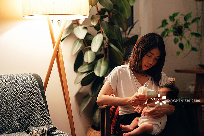 夜晚喂女儿时感到疲惫的母亲图片素材