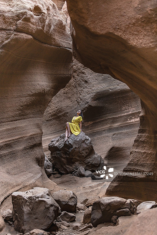 坐在峡谷岩石上的黄裙女子图片素材