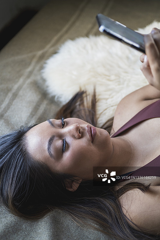 年轻女人躺在床上使用手机图片素材