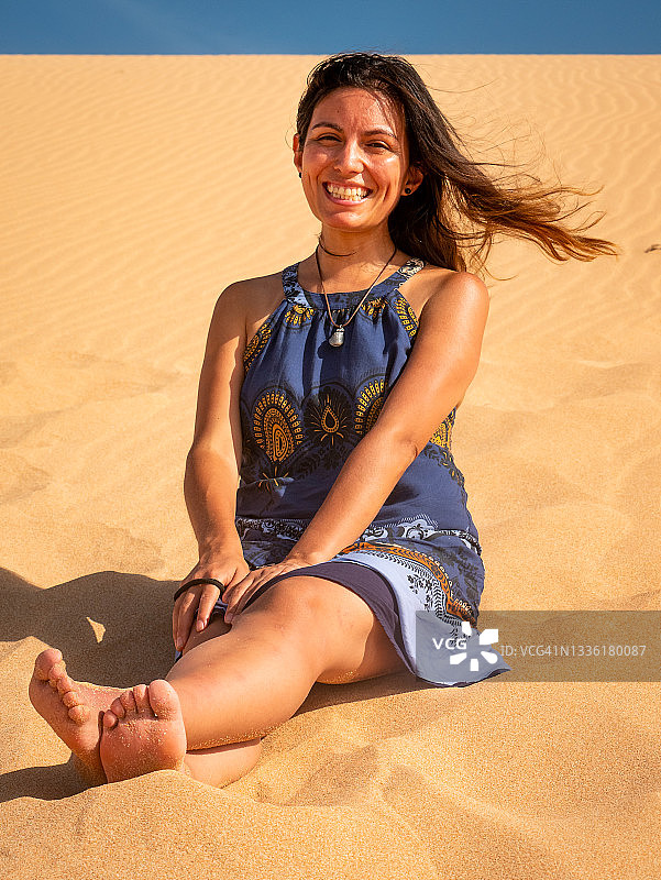 年轻拉丁裔女性坐在沙滩上图片素材