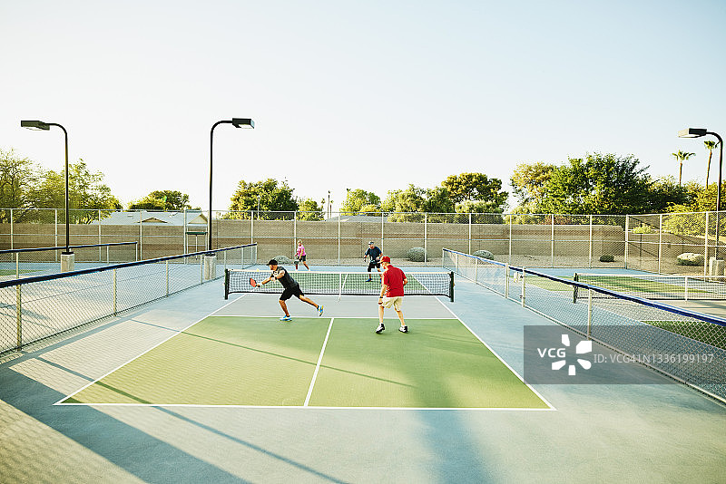 老年朋友在阳光明媚的夏日傍晚打匹克球双打的超广角镜头图片素材