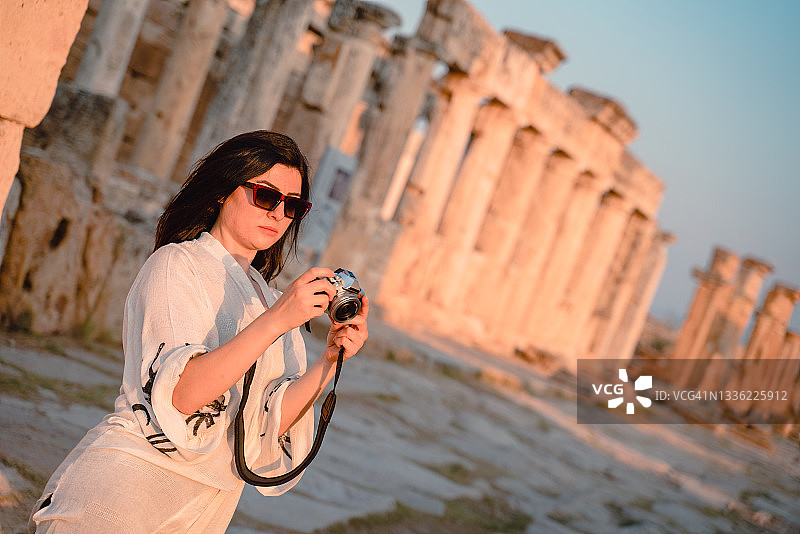 女游客在希拉波利斯古城弗朗提努斯门前拍照，棉花堡图片素材